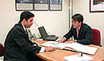 Fotograf&iacute;a de dos hombres en traje hablando en una oficina